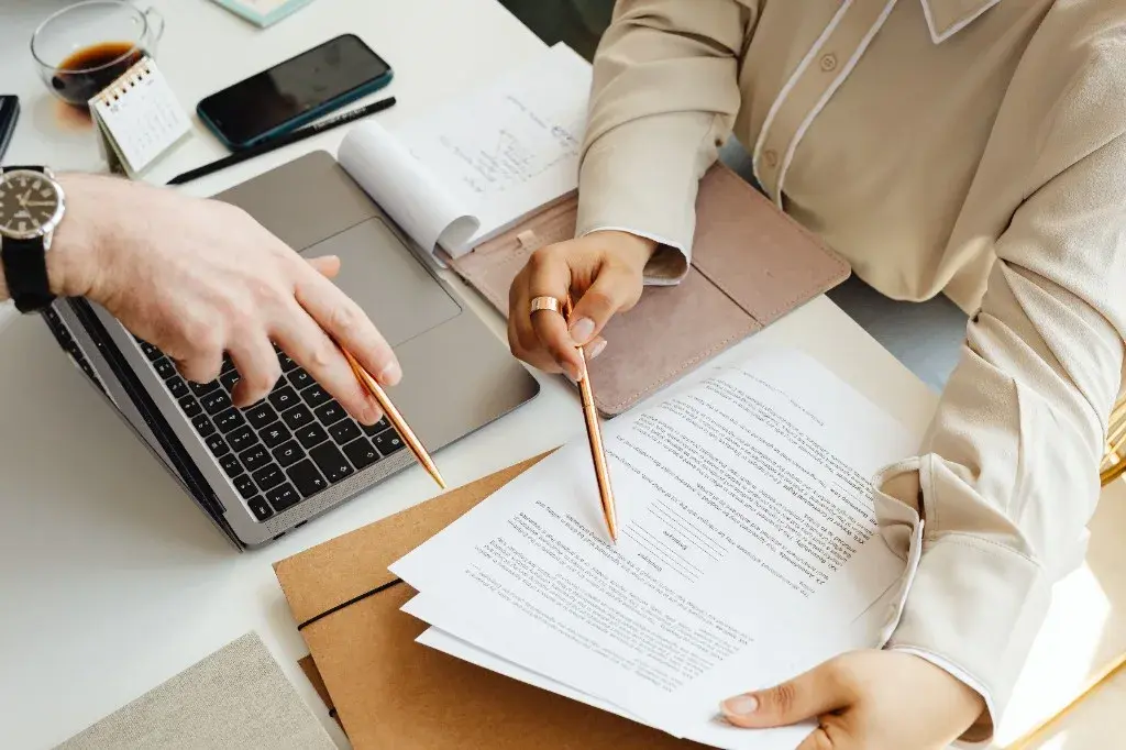 Counsel reviewing and annotating instruction documents together at a desk