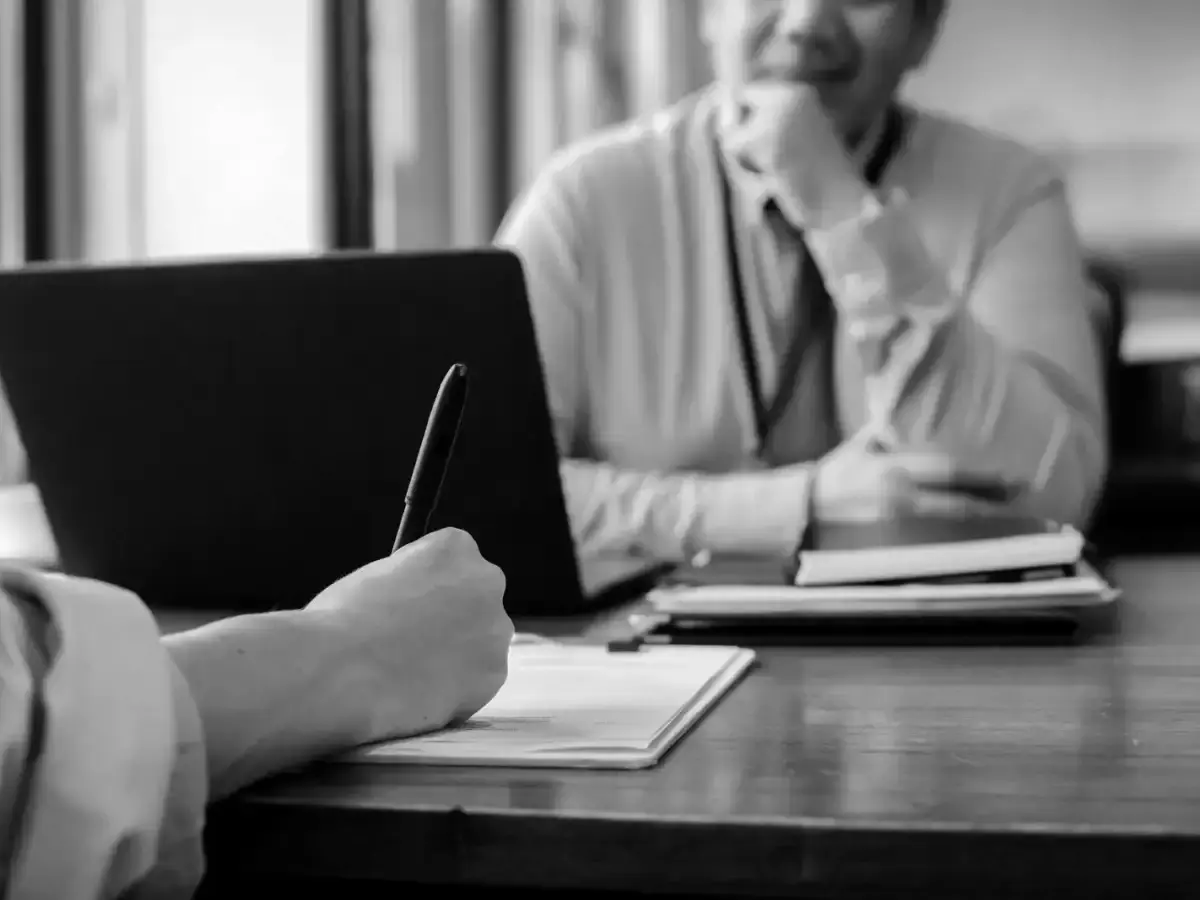 Counsel taking notes across a desk during a briefing