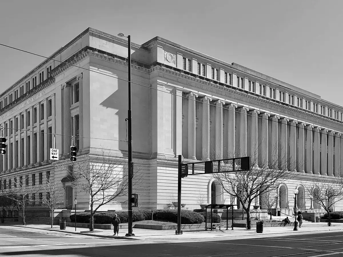 Stone courthouse with a long colonnade seen from the street corner